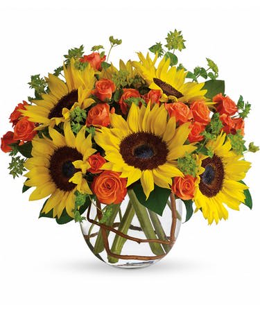 Sunflowers and orange roses arranged in a clear glass vase