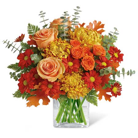 Autumn bouquet of orange roses and red-yellow mums in a clear glass vase