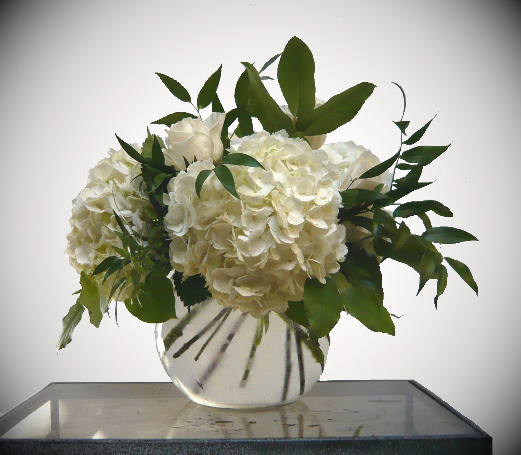 White hydrangea and rose arrangement in a clear glass vase