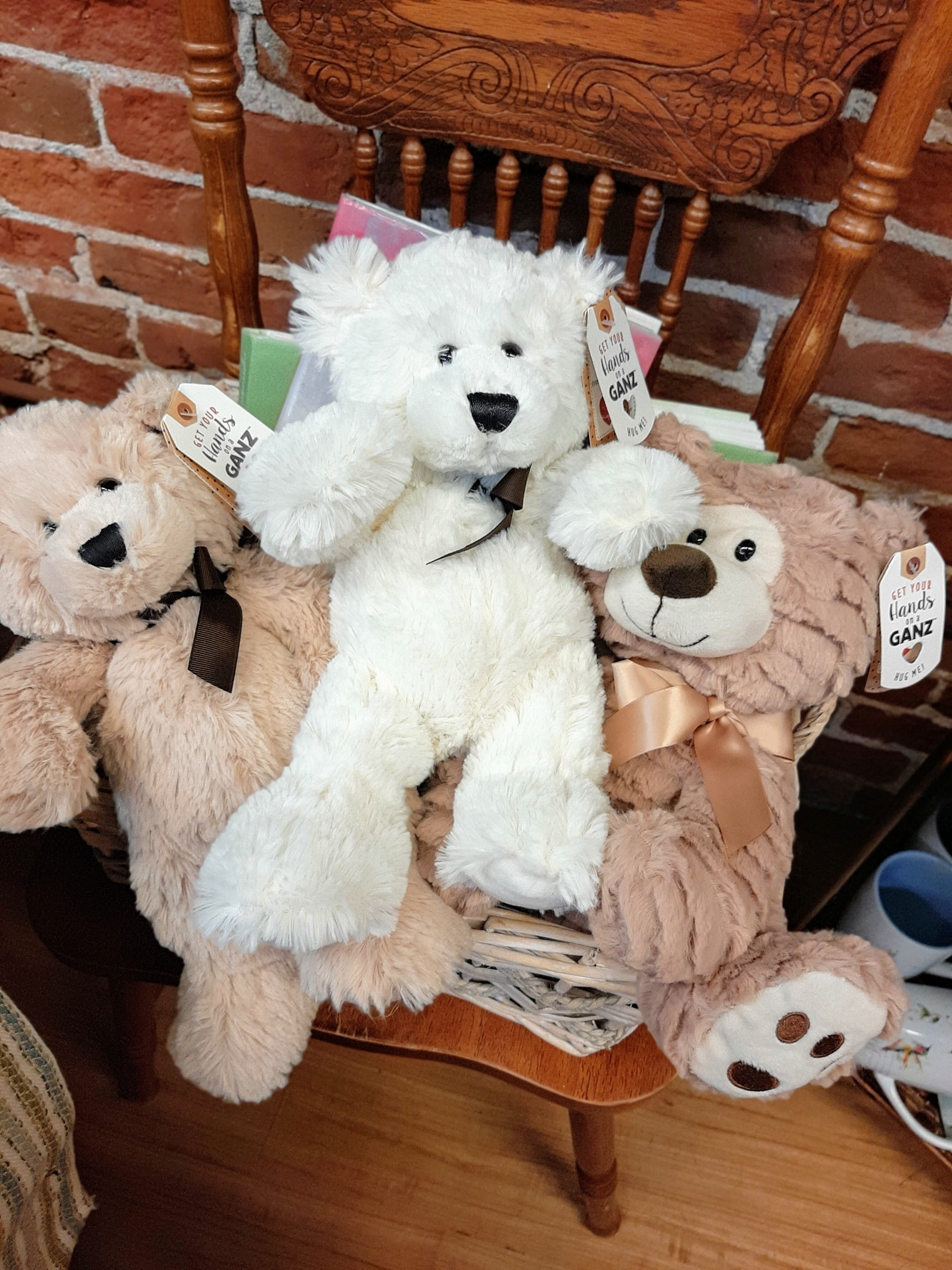 Three plush teddy bears in a basket on a wooden chair