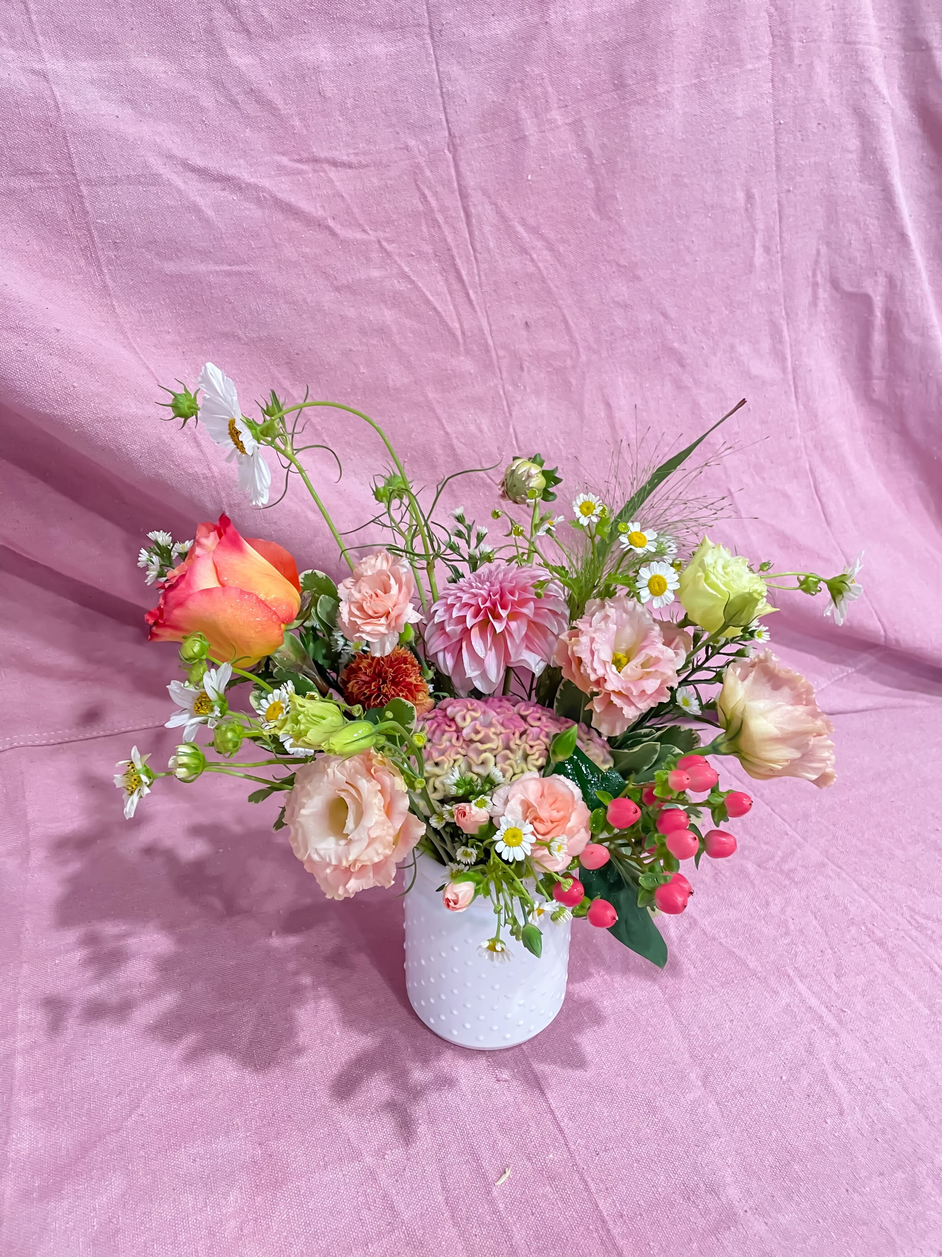 Mixed bouquet in a white textured vase with pink, peach, and white blooms