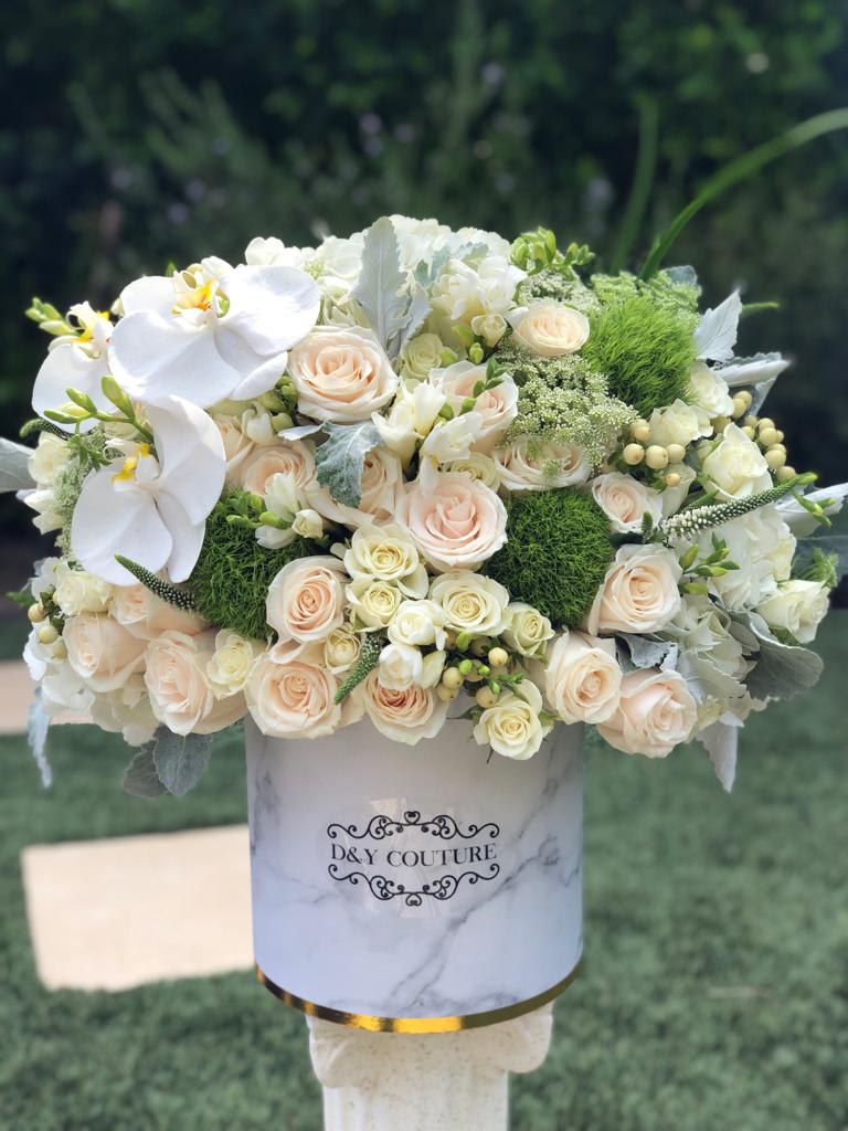 White and blush bouquet with orchids and roses in a marble-print box