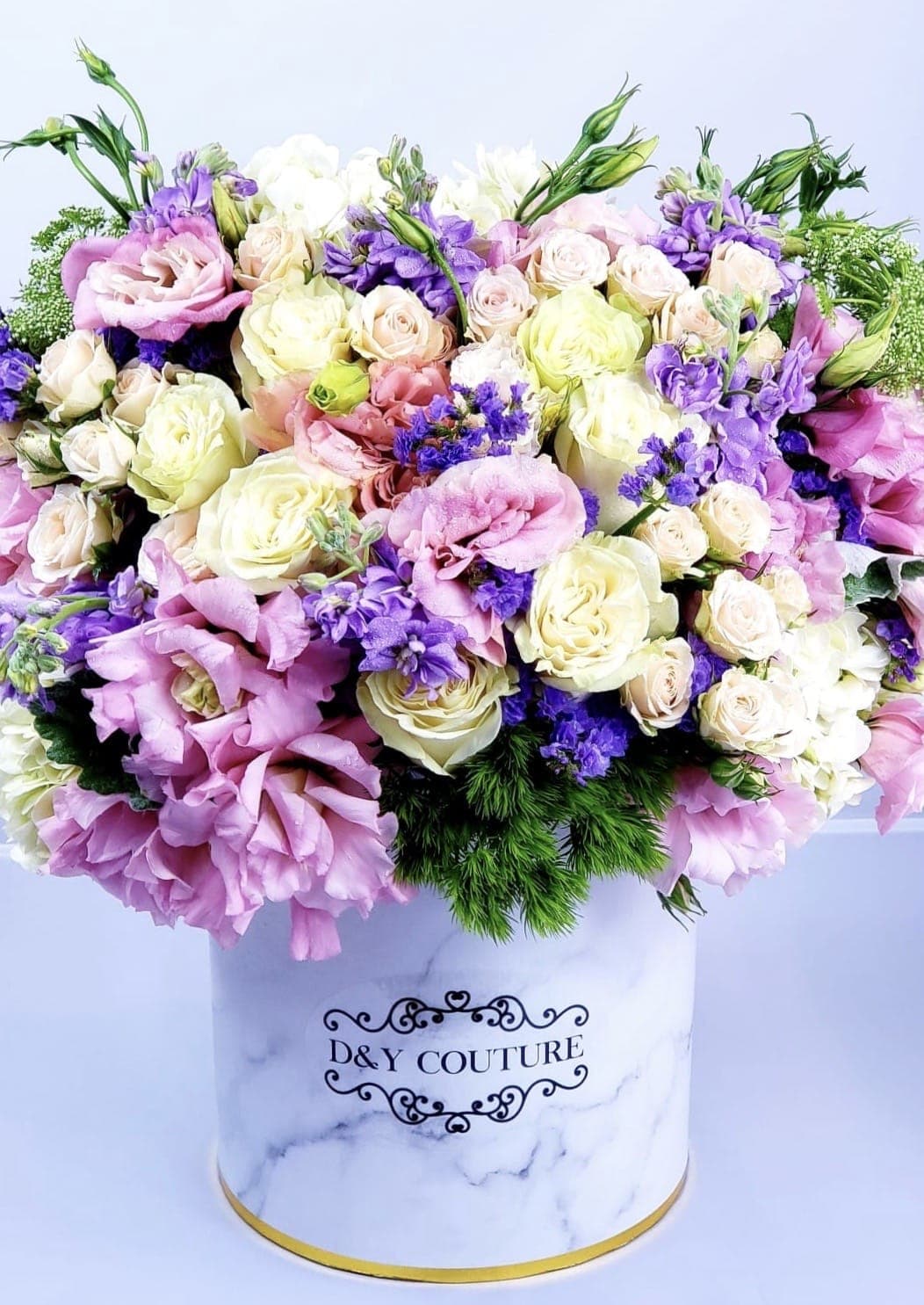 Large pastel bouquet of roses and purple blooms in a white hat box