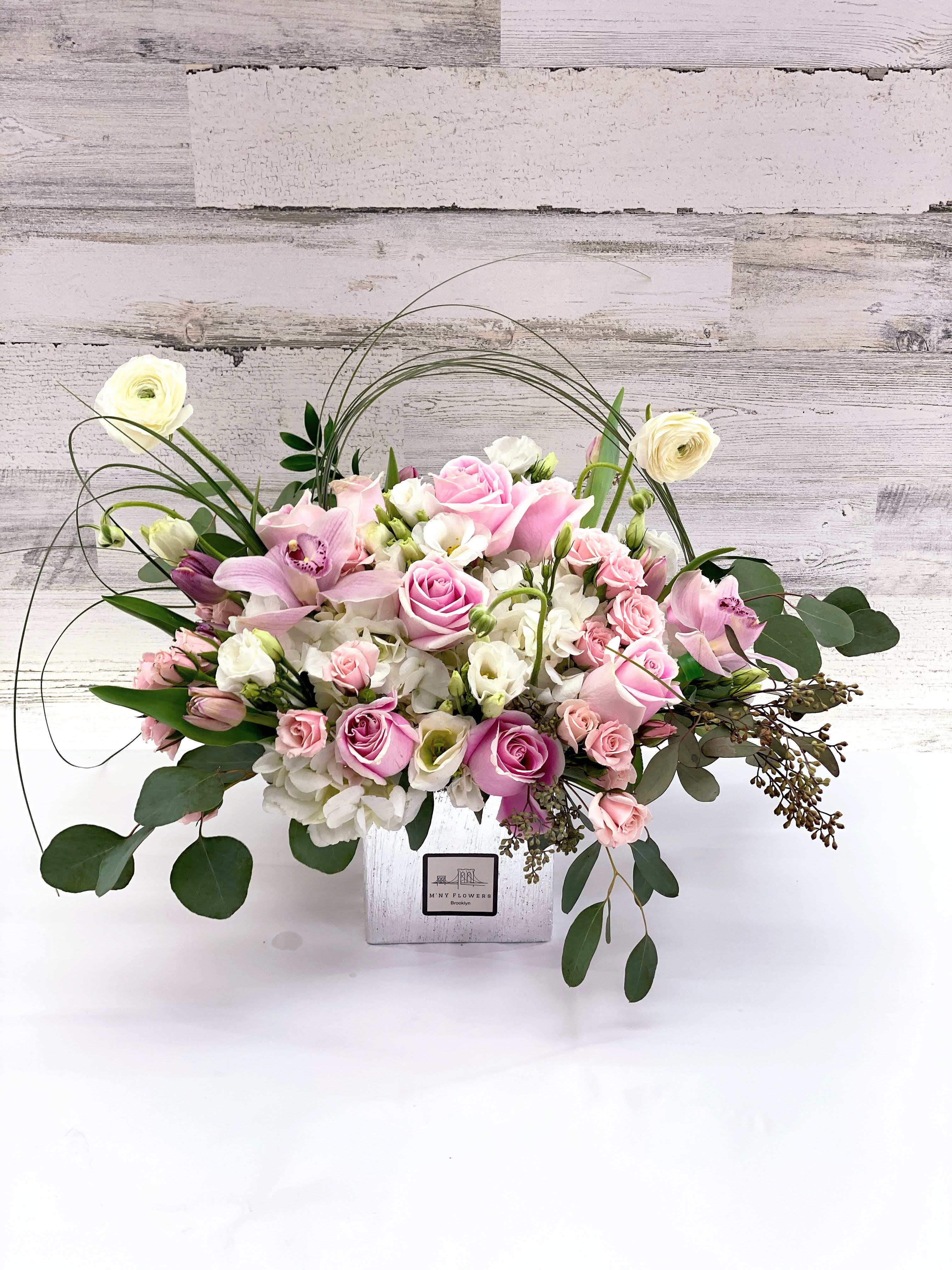 Pink and white floral arrangement in a square white vase