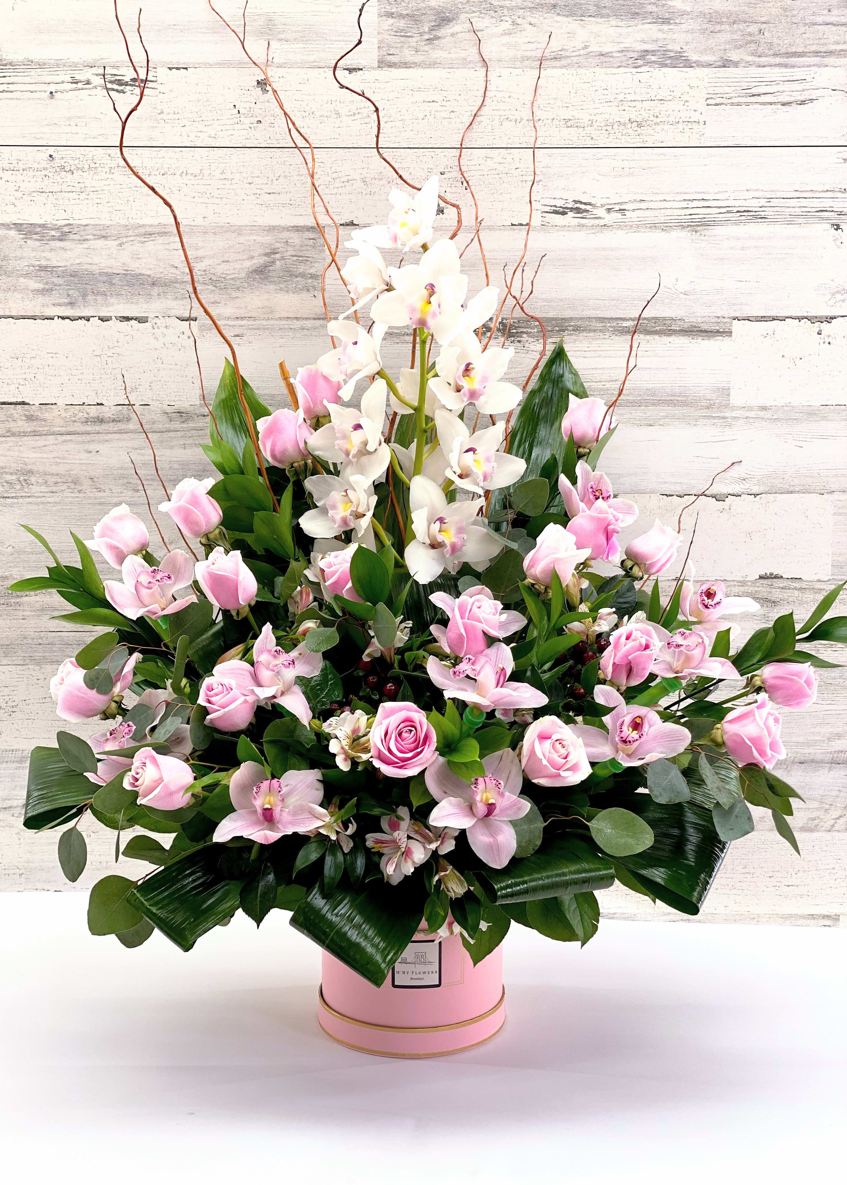 Pink roses and white orchids in a pink hatbox arrangement