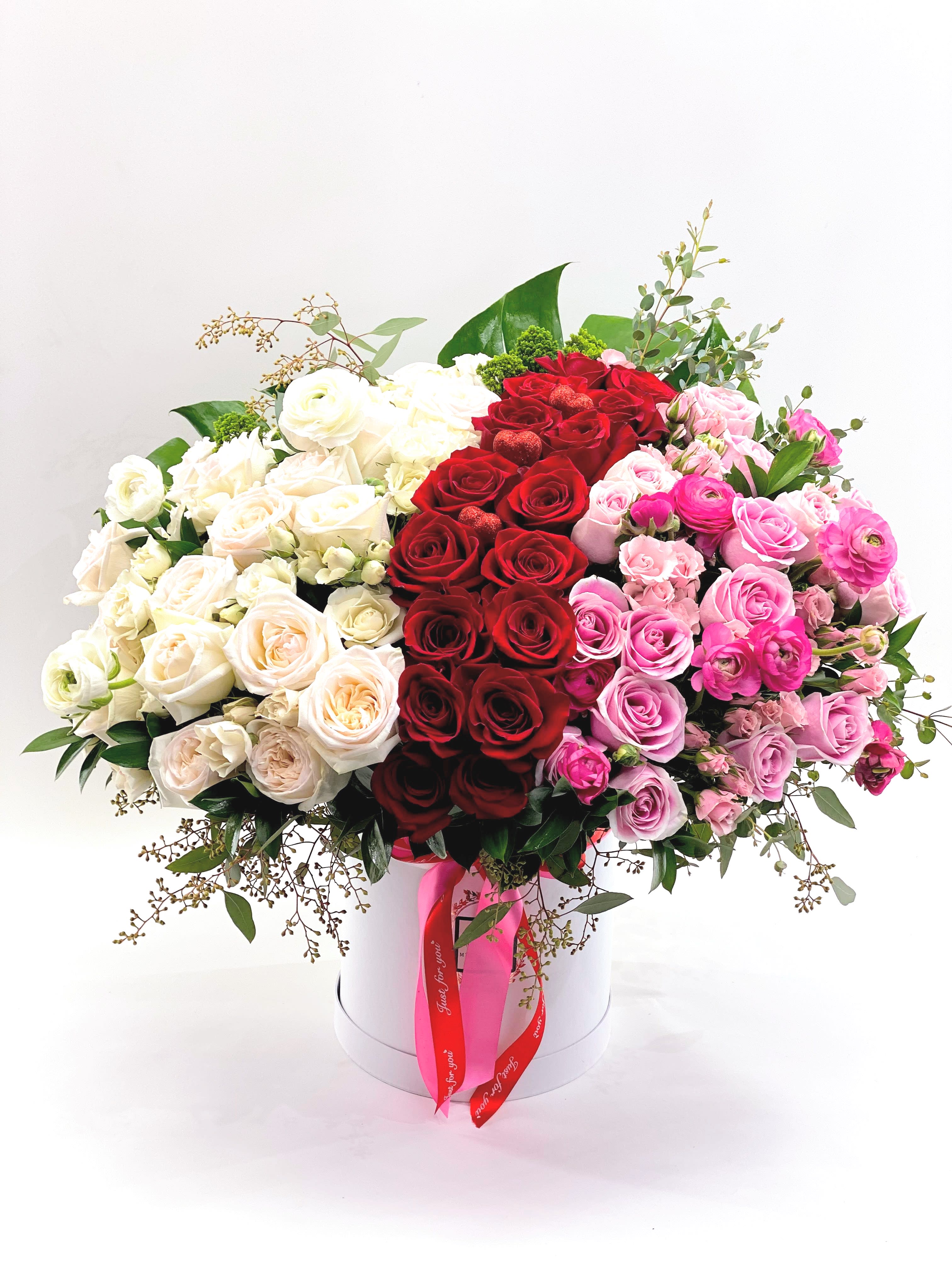 Large bouquet of red, white, and pink roses in a white hat box