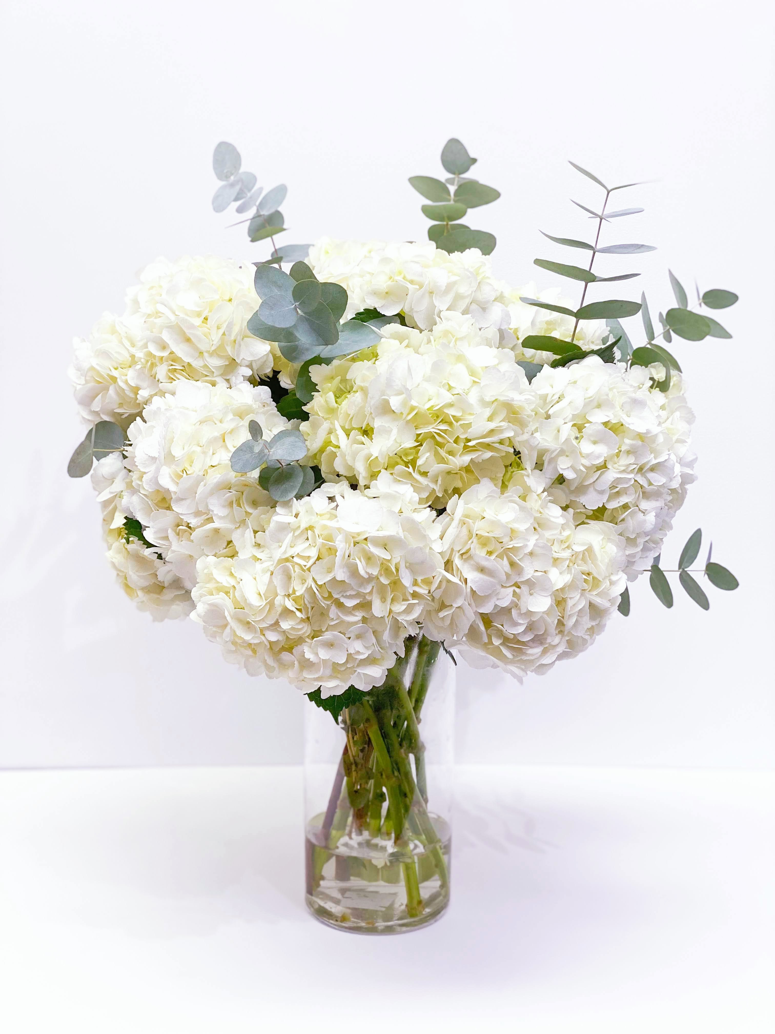 White hydrangea bouquet in a clear glass vase with eucalyptus