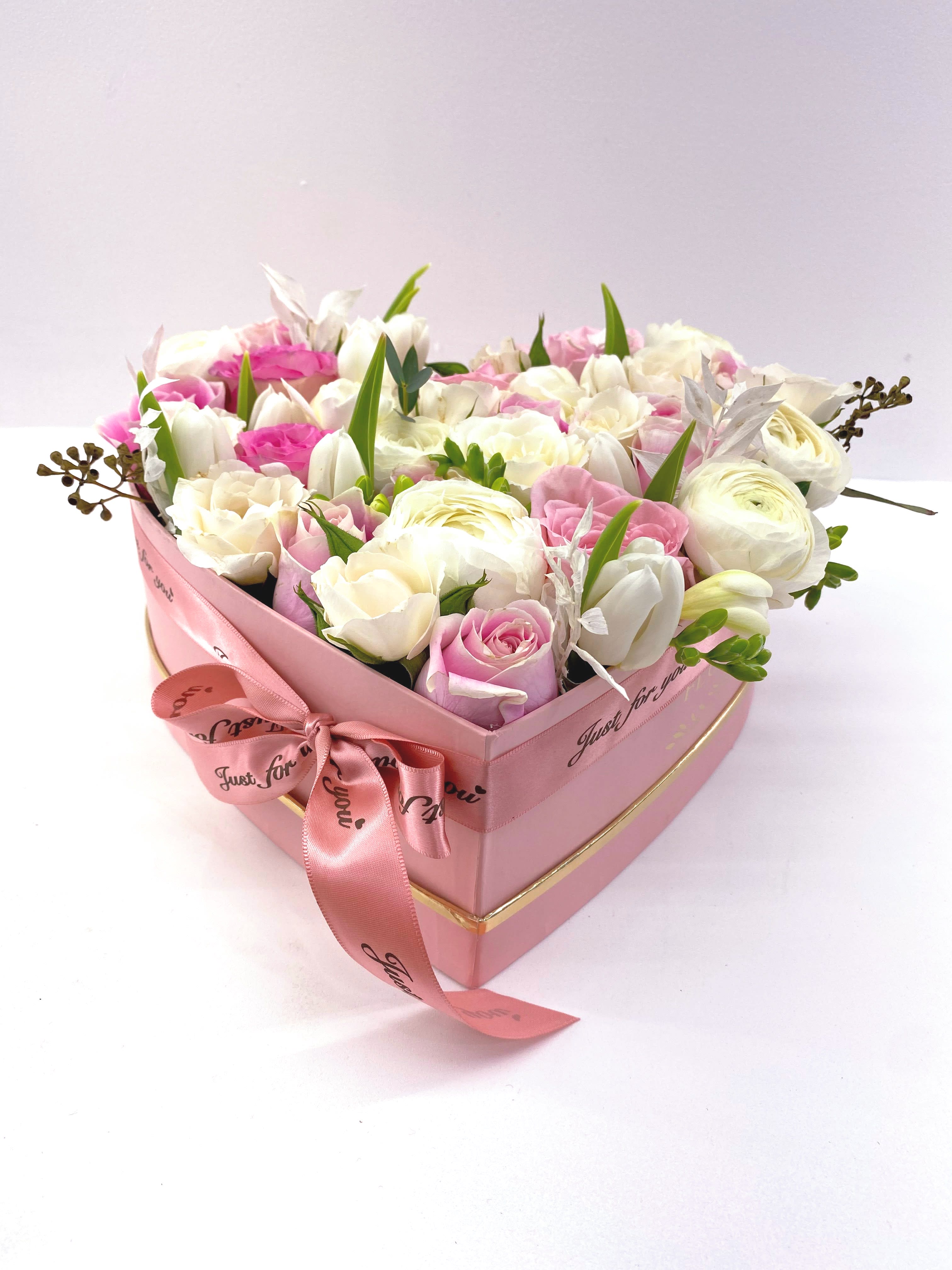 Pink heart-shaped box of white and pink roses with a ribbon bow