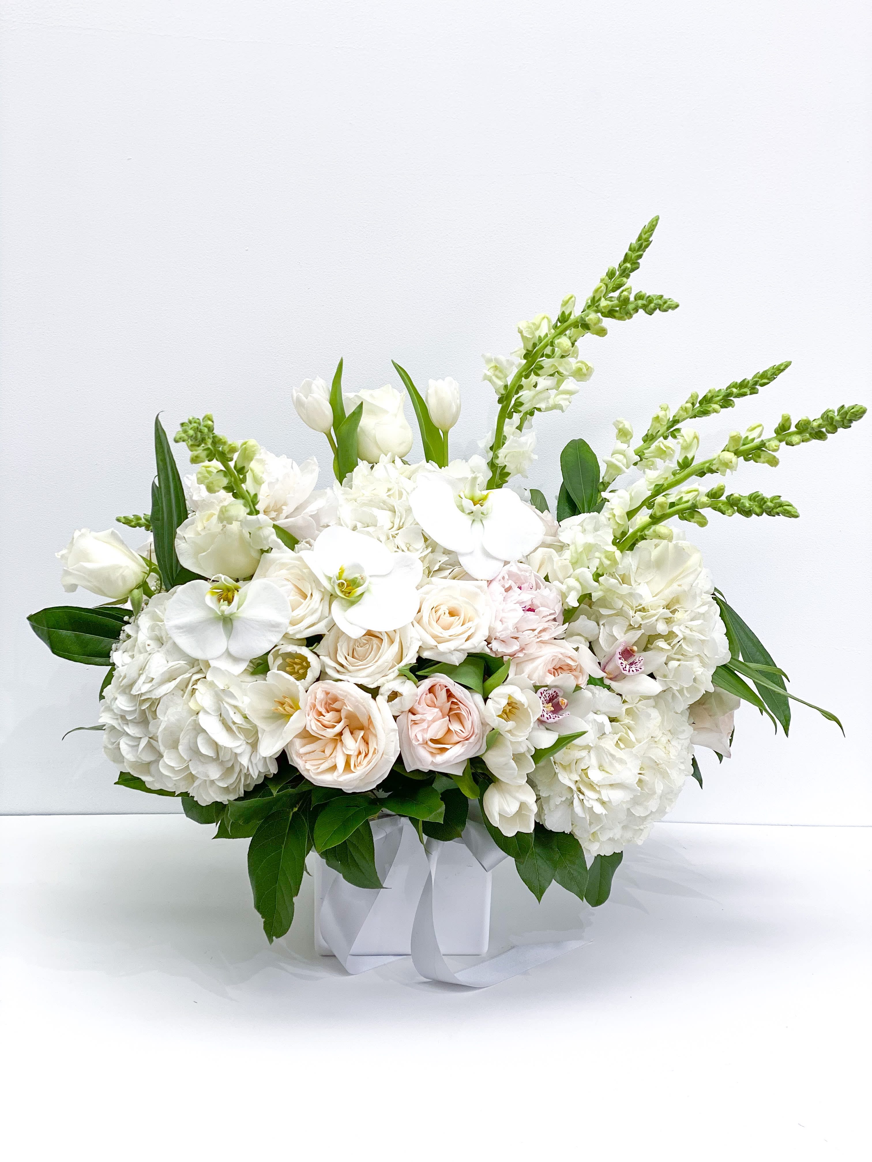 White floral arrangement in a square box with pale pink roses