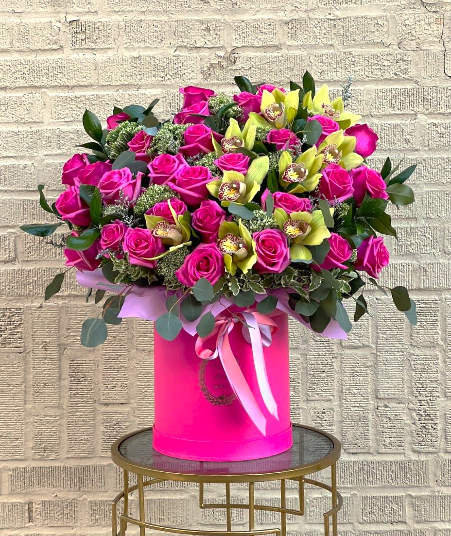 Large bouquet of pink roses and yellow orchids in a pink hat box