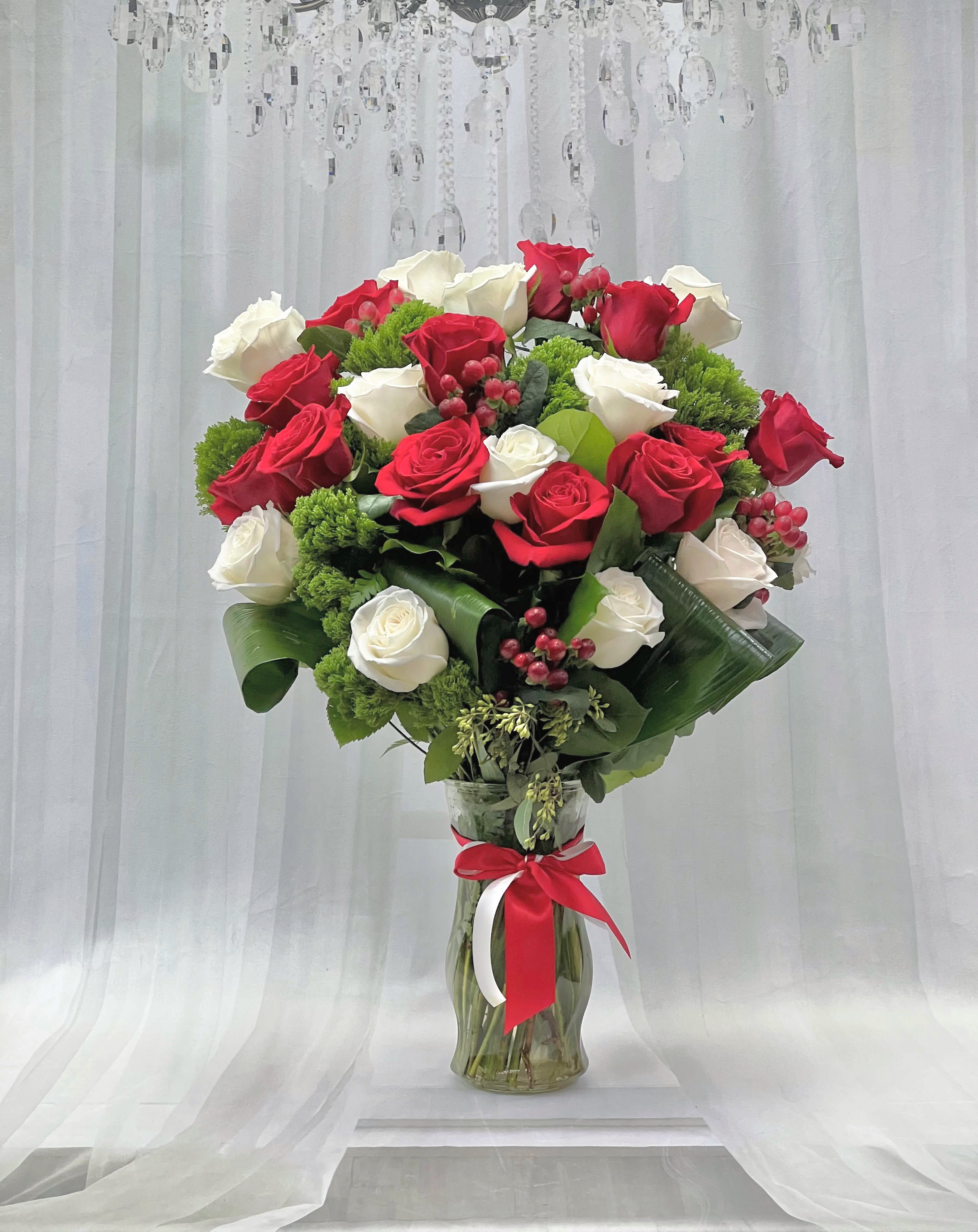 Red and white roses in a glass vase with a red ribbon