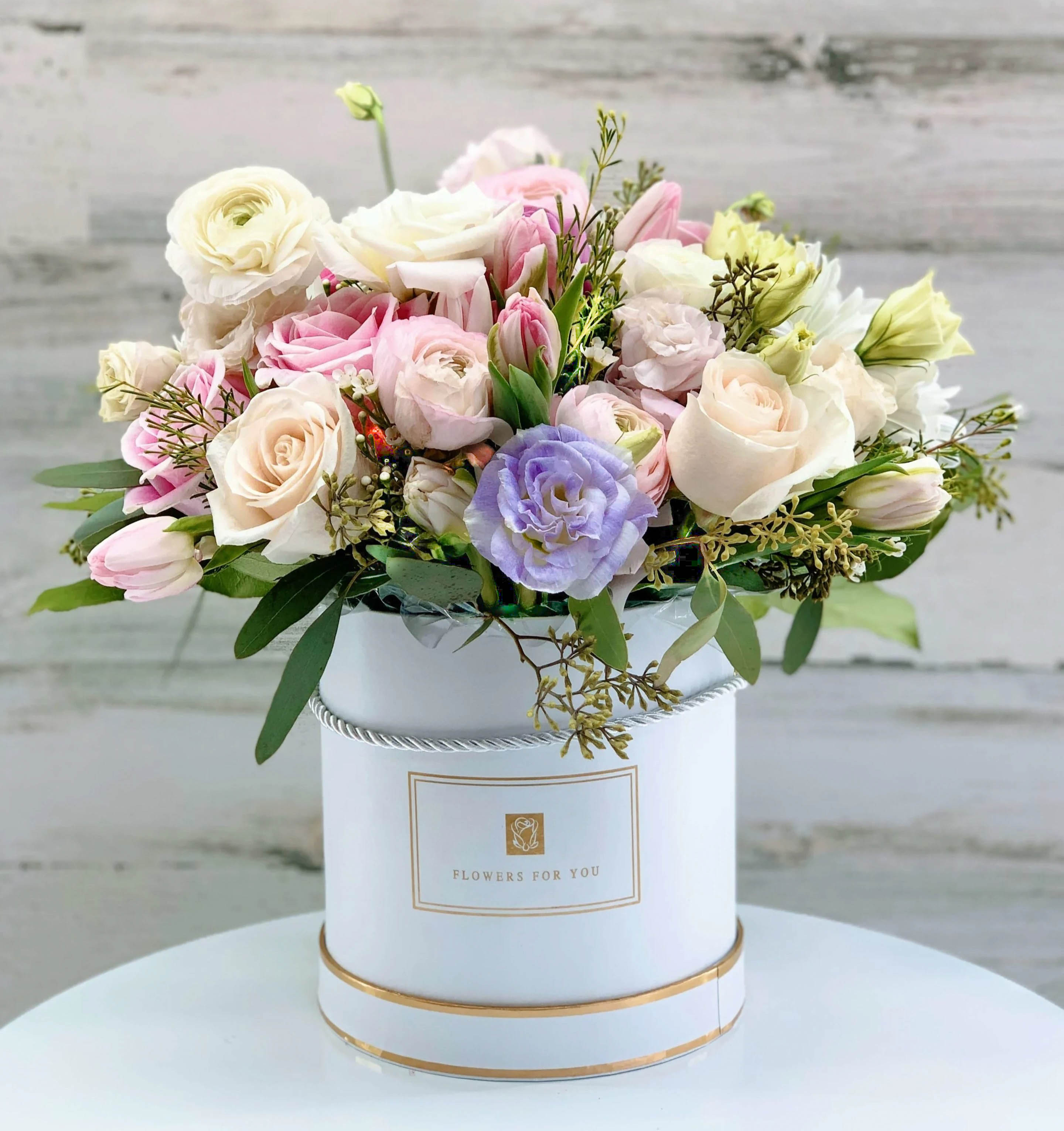 Pastel bouquet of roses and tulips in a white hatbox