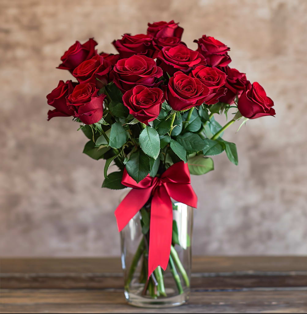 Bouquet of red roses in a clear glass vase with a red ribbon
