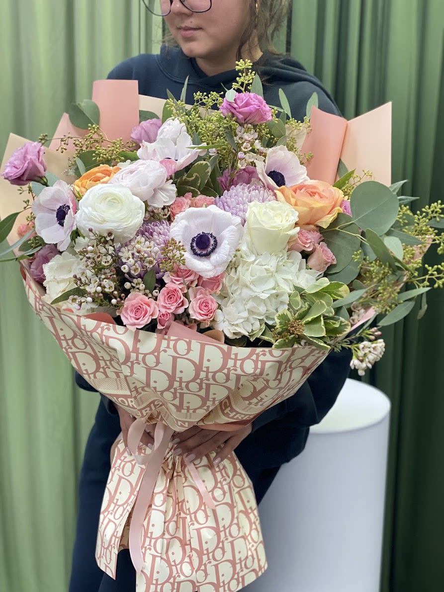 Large bouquet of pink, white, and peach flowers wrapped in patterned paper