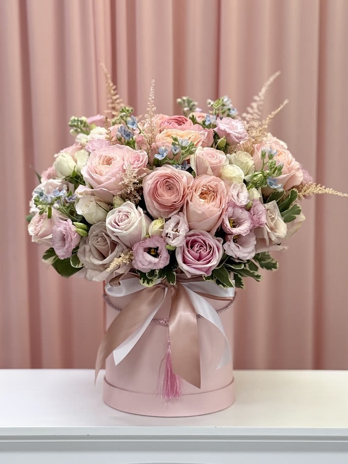 Pink and cream rose bouquet in a round hatbox with ribbon