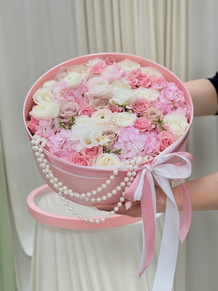 Adelina  - A luxurious floral hatbox designed in soft blush and ivory tones, featuring premium roses, ranunculus, hydrangeas, and delicate orchids. Finished with elegant pearl accents and satin ribbons, this arrangement brings together timeless romance and modern sophistication.  Perfect for birthdays, bridal celebrations, baby showers, anniversaries, or any unforgettable occasion. Each composition is carefully handcrafted by MNY Flowers using fresh seasonal blooms selected for their beauty and quality.