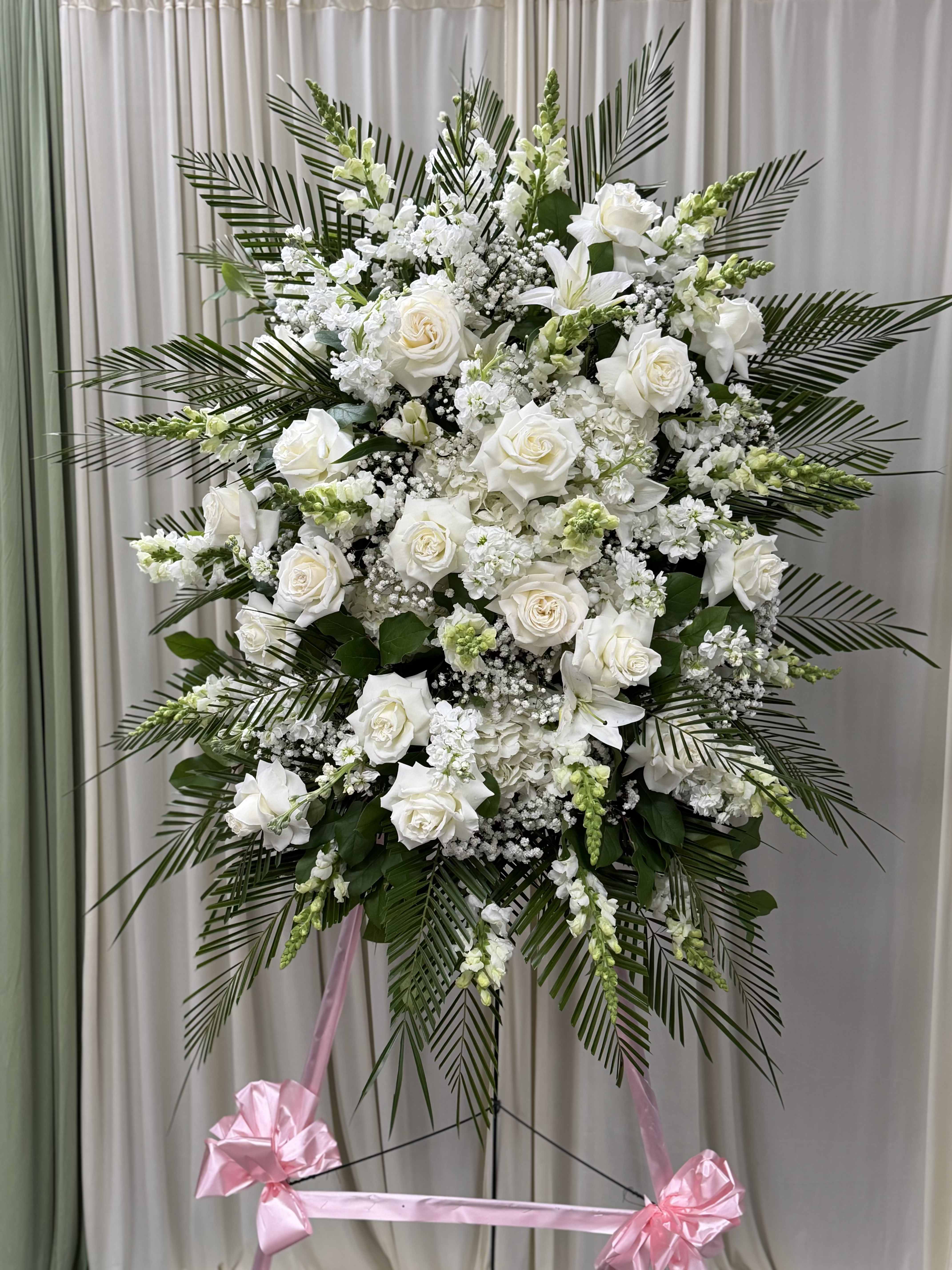 Forever Feelings by M'NY'Flowers. - White is the color of love and this standing spray displays it with luxurious style. White roses and palms come together with other flowers and greenery to create a beautiful salute.