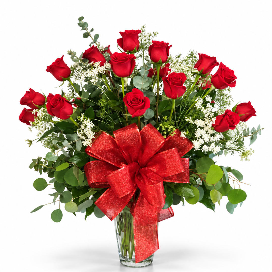 Red roses in a clear glass vase with a large red bow