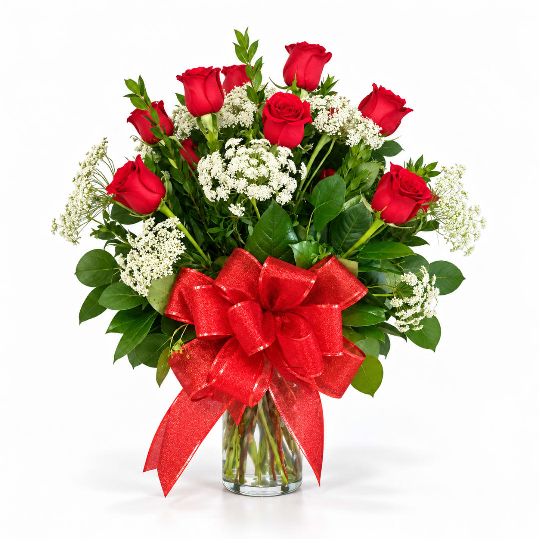 Red roses in a clear glass vase with a large red bow
