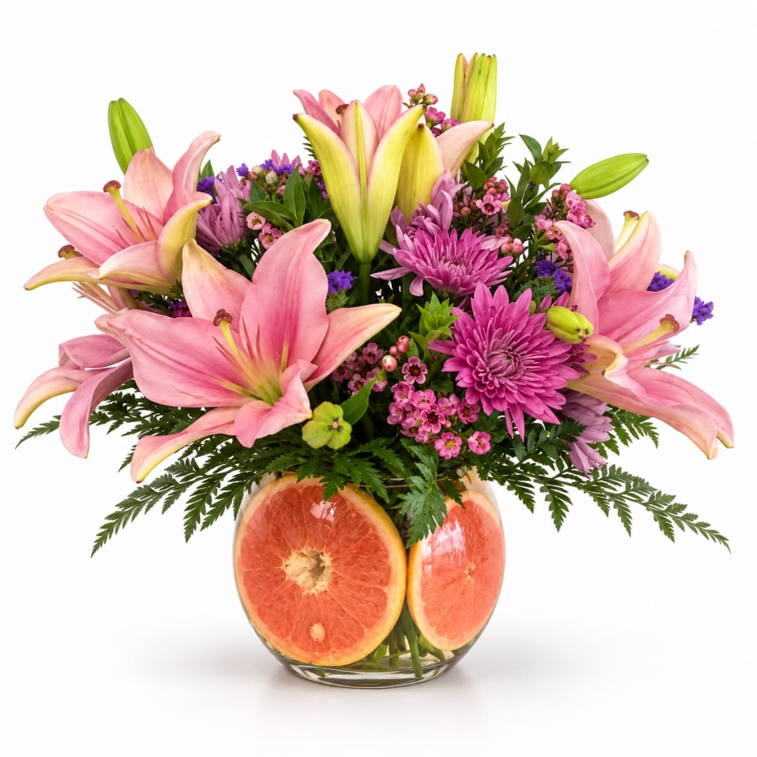 Pink lilies and purple flowers in a glass vase with grapefruit slices