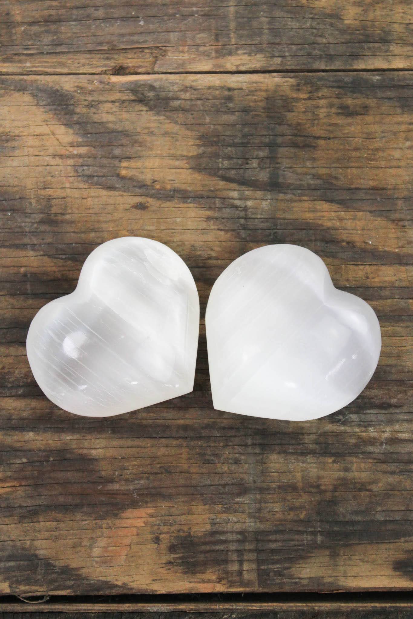 Two white heart-shaped stones on a wooden surface