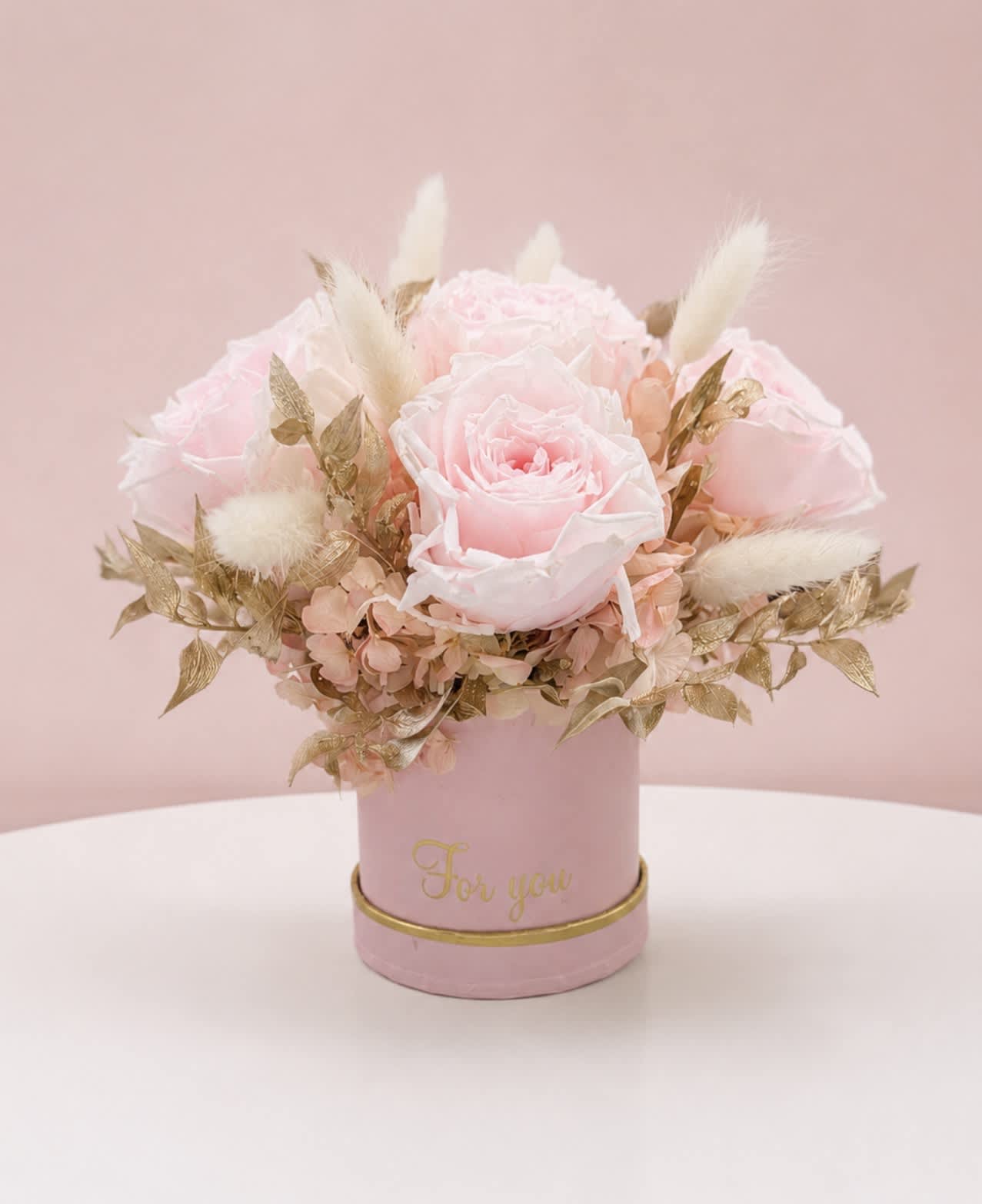 Pink rose arrangement in a round box with gold accents