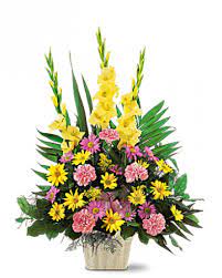 Tall mixed floral arrangement in a square vase with yellow and pink blooms