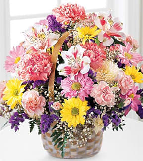 Mixed bouquet of pink, yellow, and purple flowers in a basket