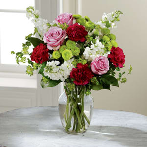 Bouquet of pink roses, red carnations, and white flowers in a glass vase