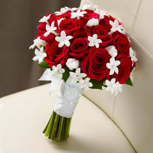 Bouquet of red roses with white star-shaped accents and a white ribbon wrap