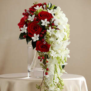 Cascade bouquet of red roses and white orchids in a clear vase