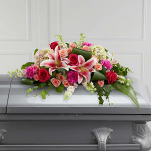 Casket spray with pink lilies and red roses