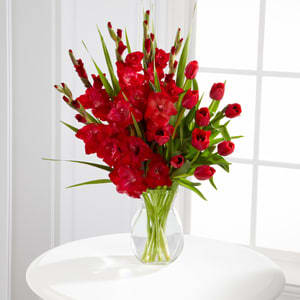 Red tulips and gladiolus in a clear glass vase
