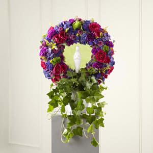 Circular floral wreath with purple, pink, and red flowers on a pedestal