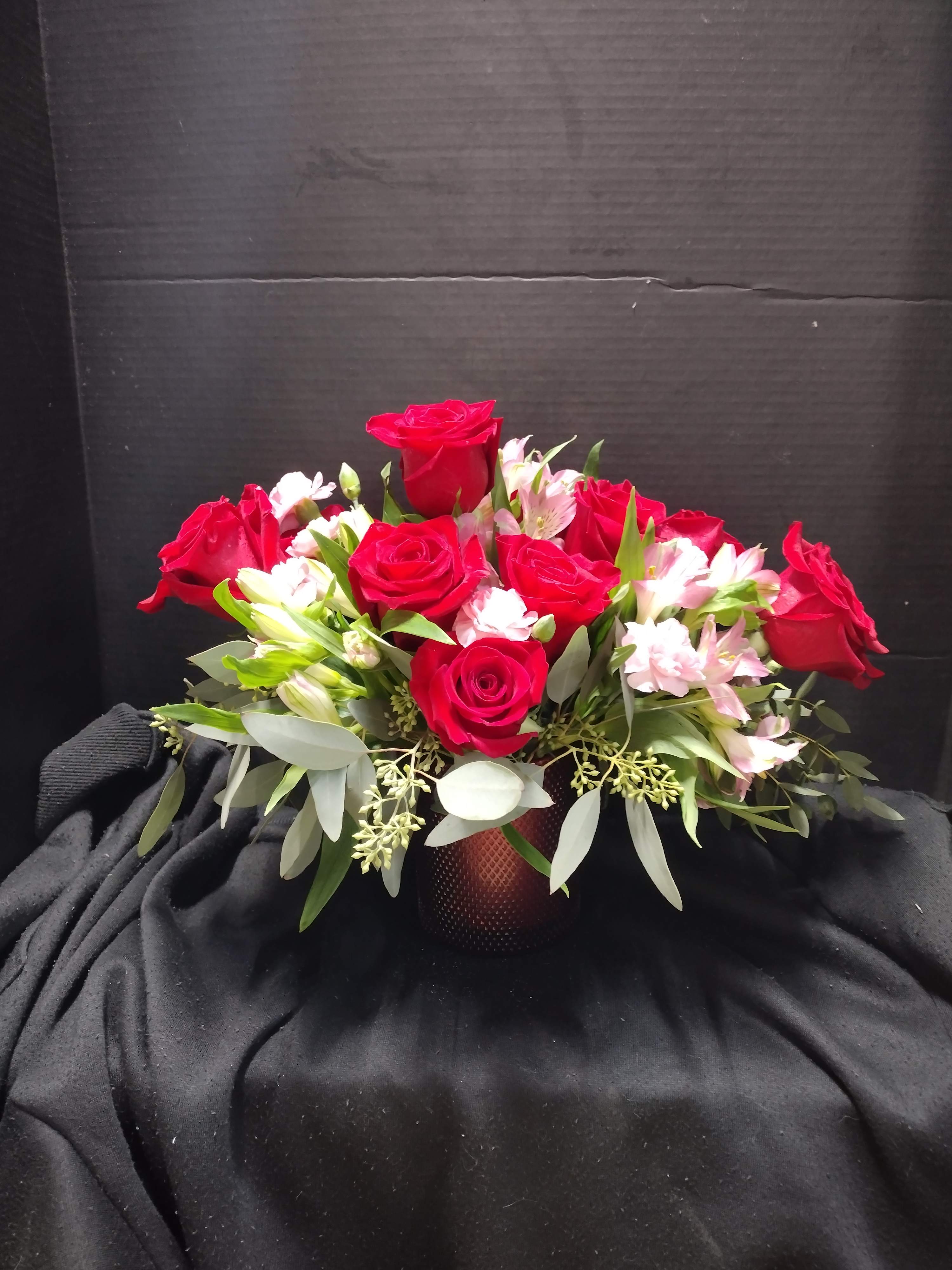 Red roses and pink alstroemeria arranged in a low vase