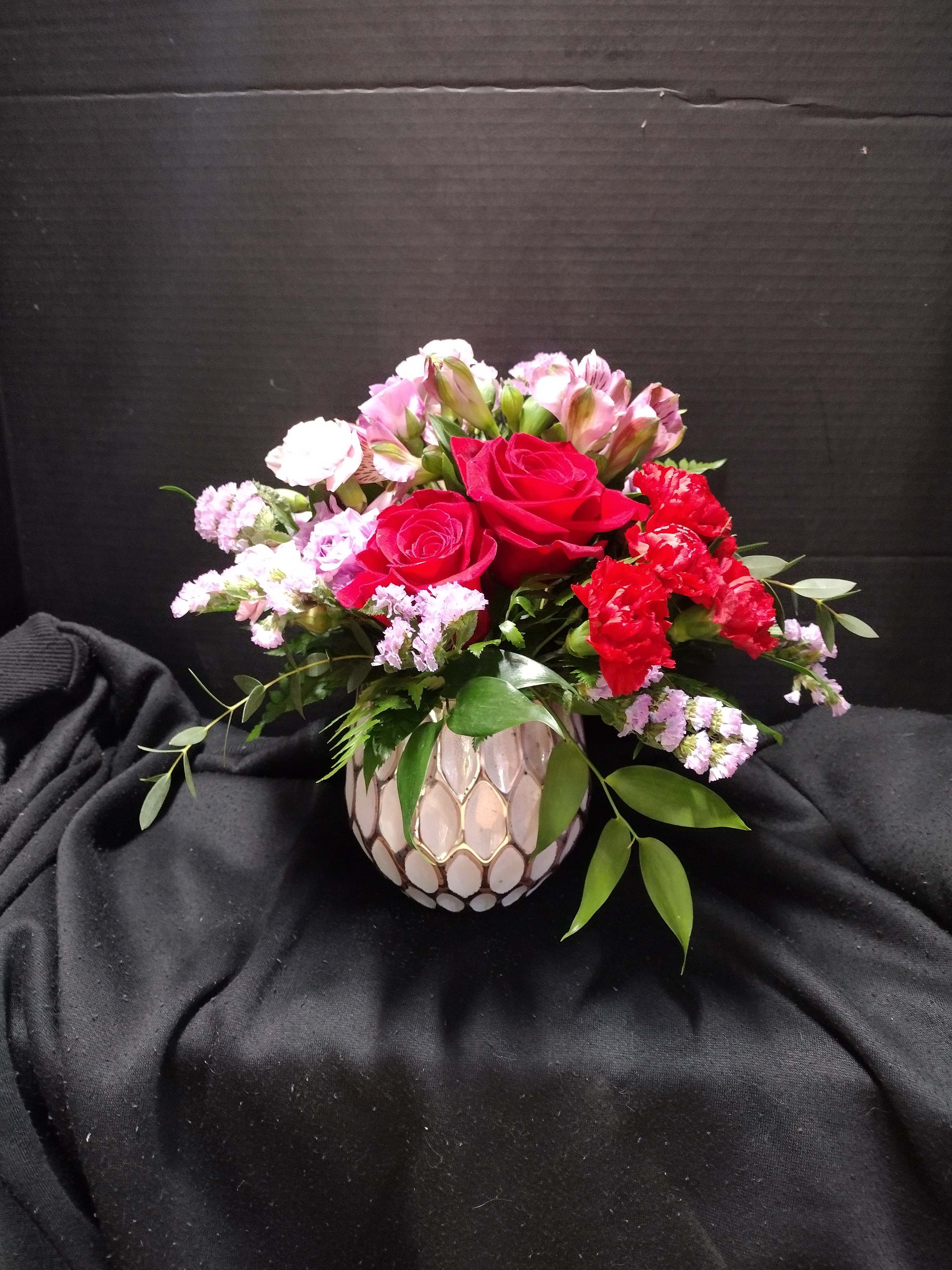 Bouquet of red roses and pink flowers in a patterned vase