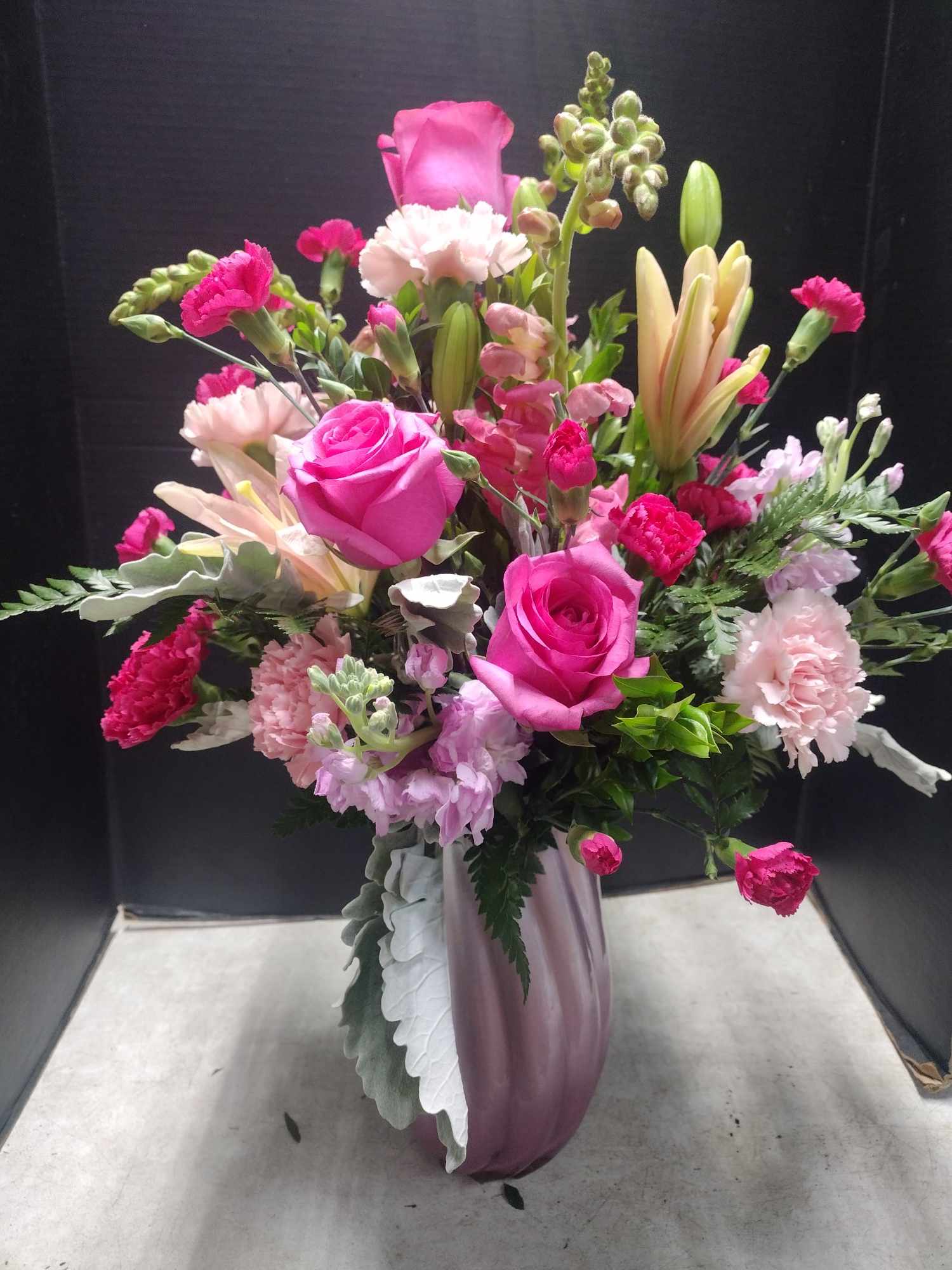 Pink rose and lily bouquet in a purple vase