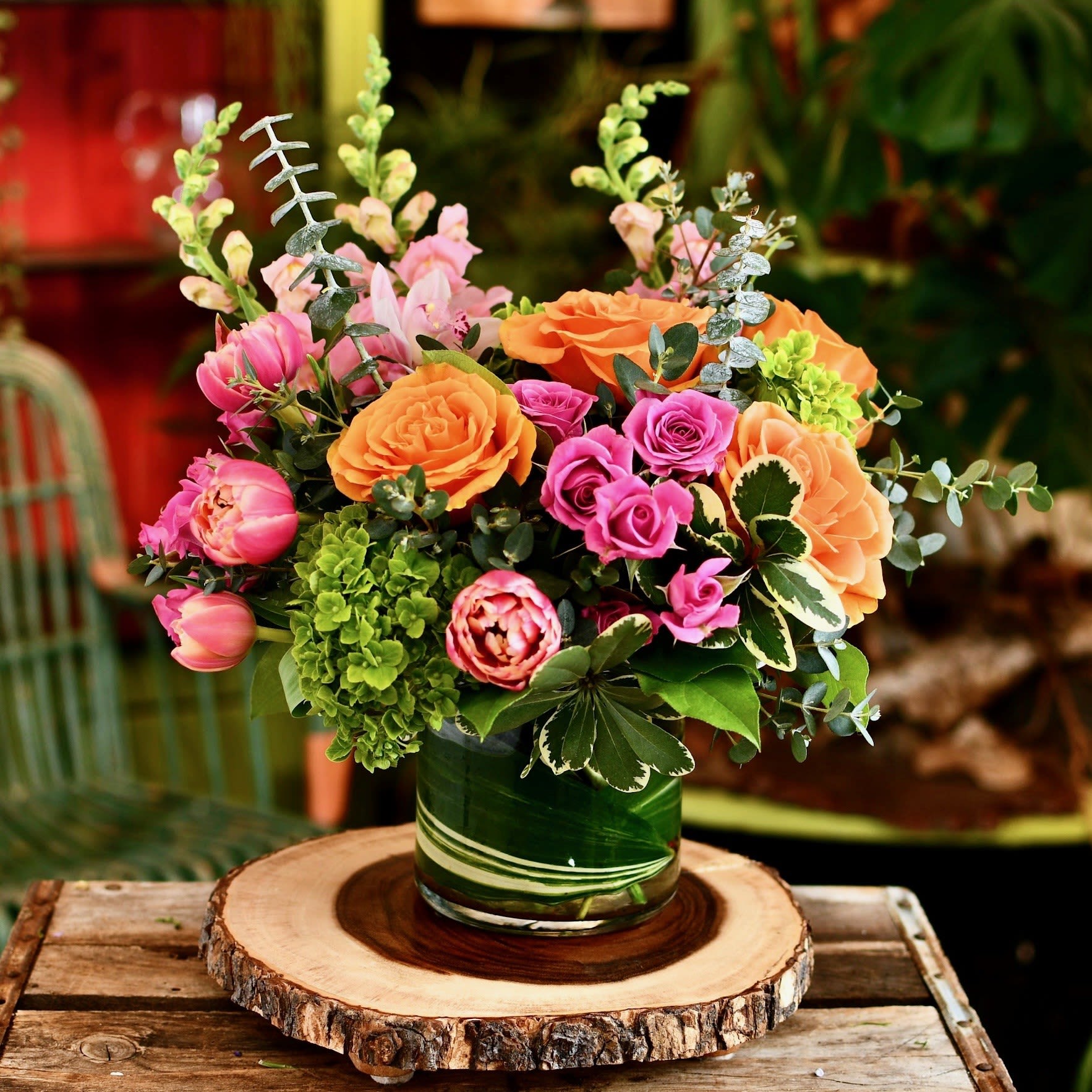 Mixed bouquet of pink and orange flowers in a green glass vase