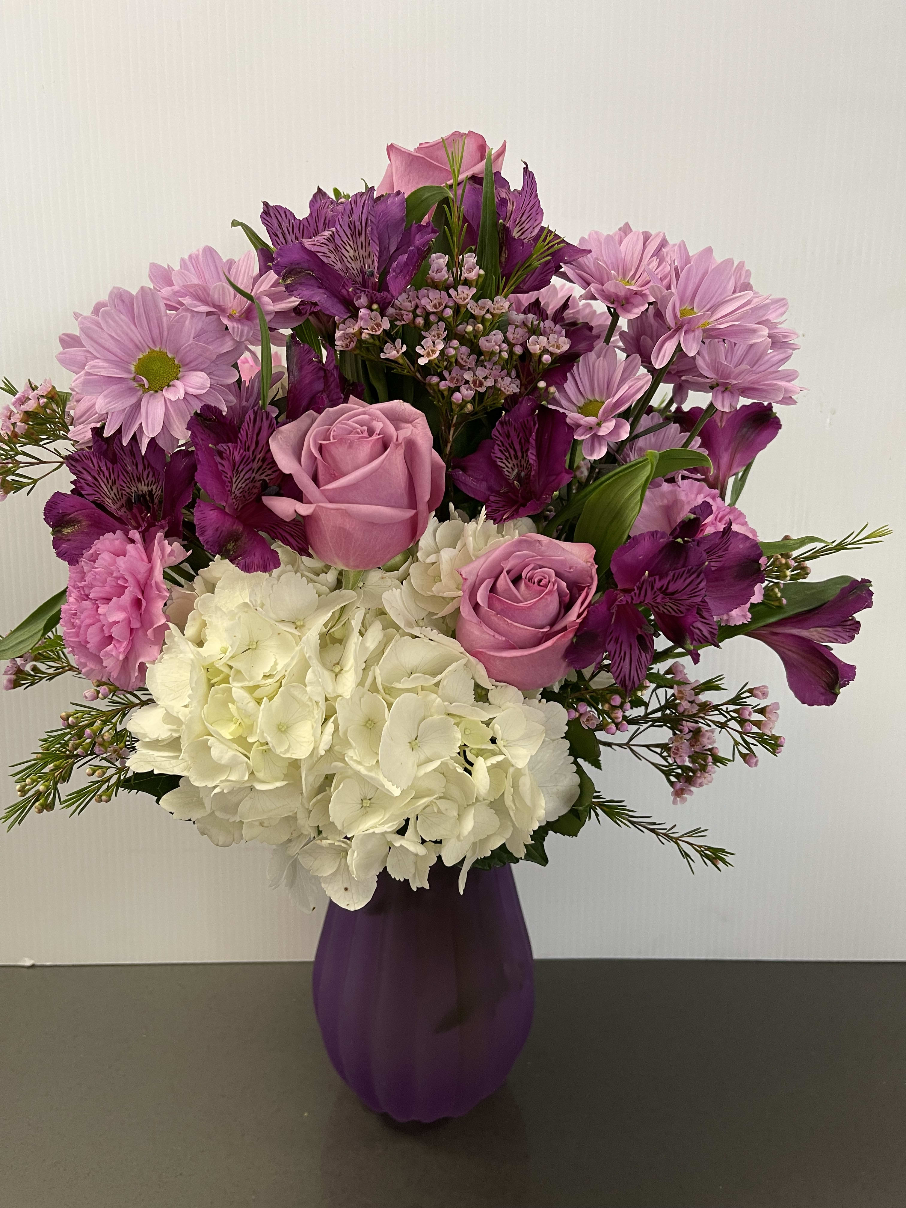 Pink and purple bouquet with roses, hydrangea, and daisies in a purple vase