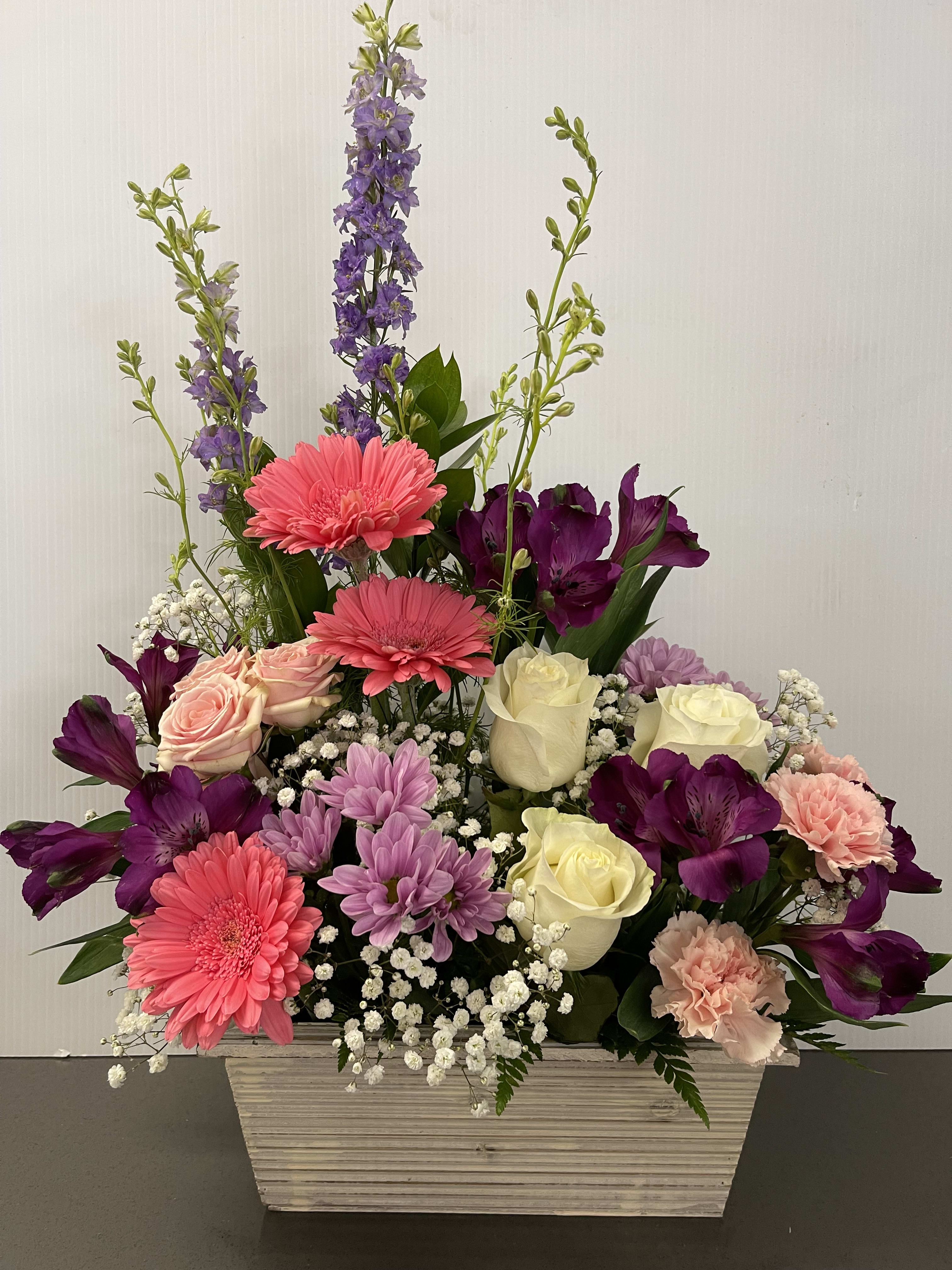 Mixed bouquet in a white rectangular container with pink, purple, and cream flowers