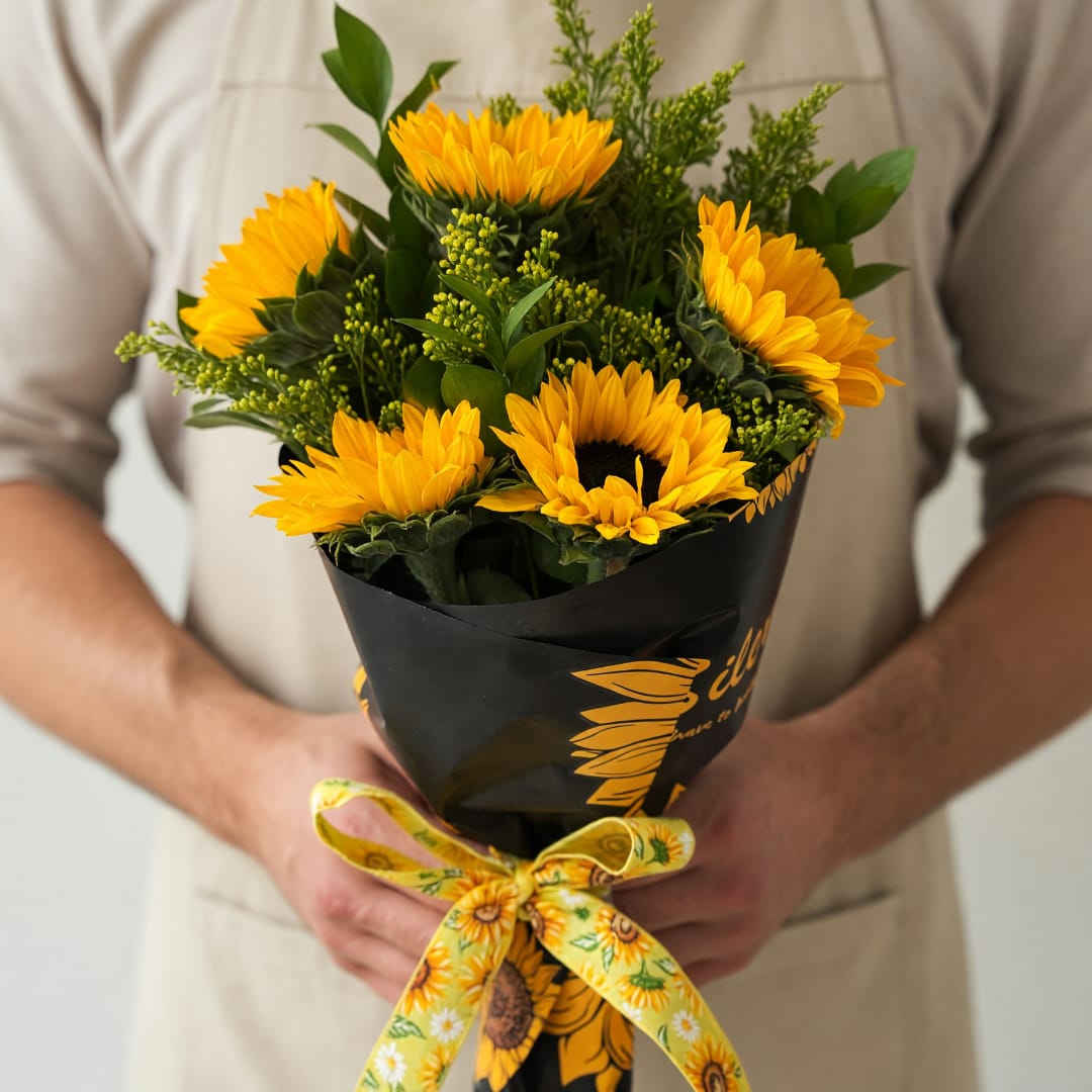Bouquet of yellow sunflowers wrapped in black paper with a yellow ribbon