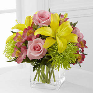 Bouquet of pink roses, yellow lilies, and pink alstroemeria in a clear vase