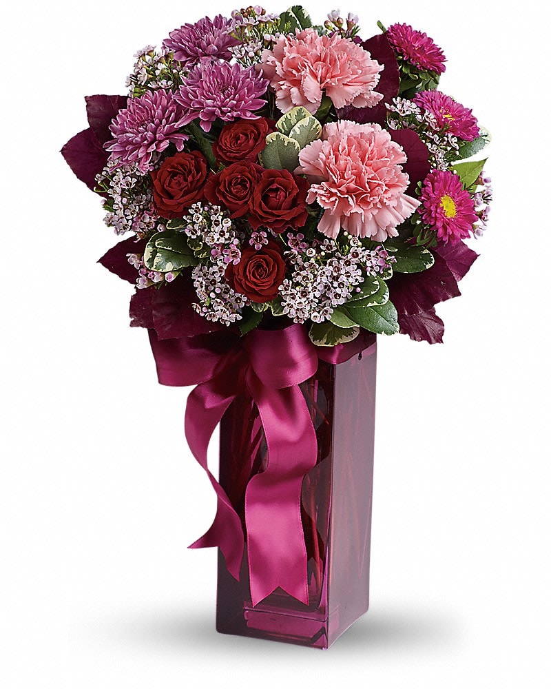 Bouquet of pink and red flowers in a tall purple vase with a ribbon