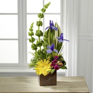 Tall mixed flower arrangement in a square brown vase