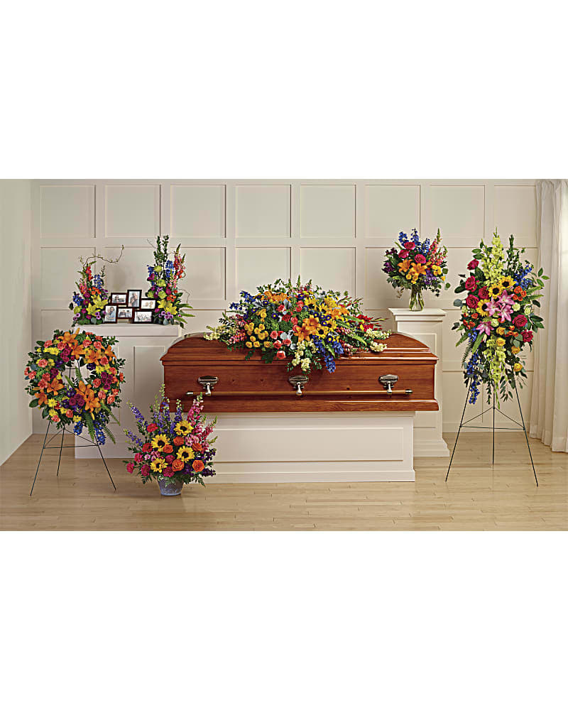 Colorful funeral casket spray with standing floral tributes