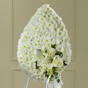 White funeral spray with lilies and roses on a stand