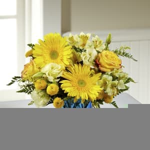 The FTD® Oh Boy! New Baby Bouquet - There is nothing in the world as magical and precious as the birth of a new baby! Celebrate the new little one with this inspiring sunlit flower bouquet, bringing together a collection of yellow blooms, including roses, gerbera daisies, Peruvian Lilies, double lisianthus, button poms, and solidago. Accented with lush greens and arranged perfectly in a modern blue glass cubed vase, this flower bouquet is ready to welcome the brand new baby boy into the world, sending your warmest wishes to the new family with this truly thoughtful gift. GOOD bouquet includes 12 stems. Approx. 12"H x 12"W. BETTER bouquet includes 15 stems. Approx. 13"H x 15"W. BEST bouquet includes 20 stems. Approx. 13"H x 16"W. (z)
