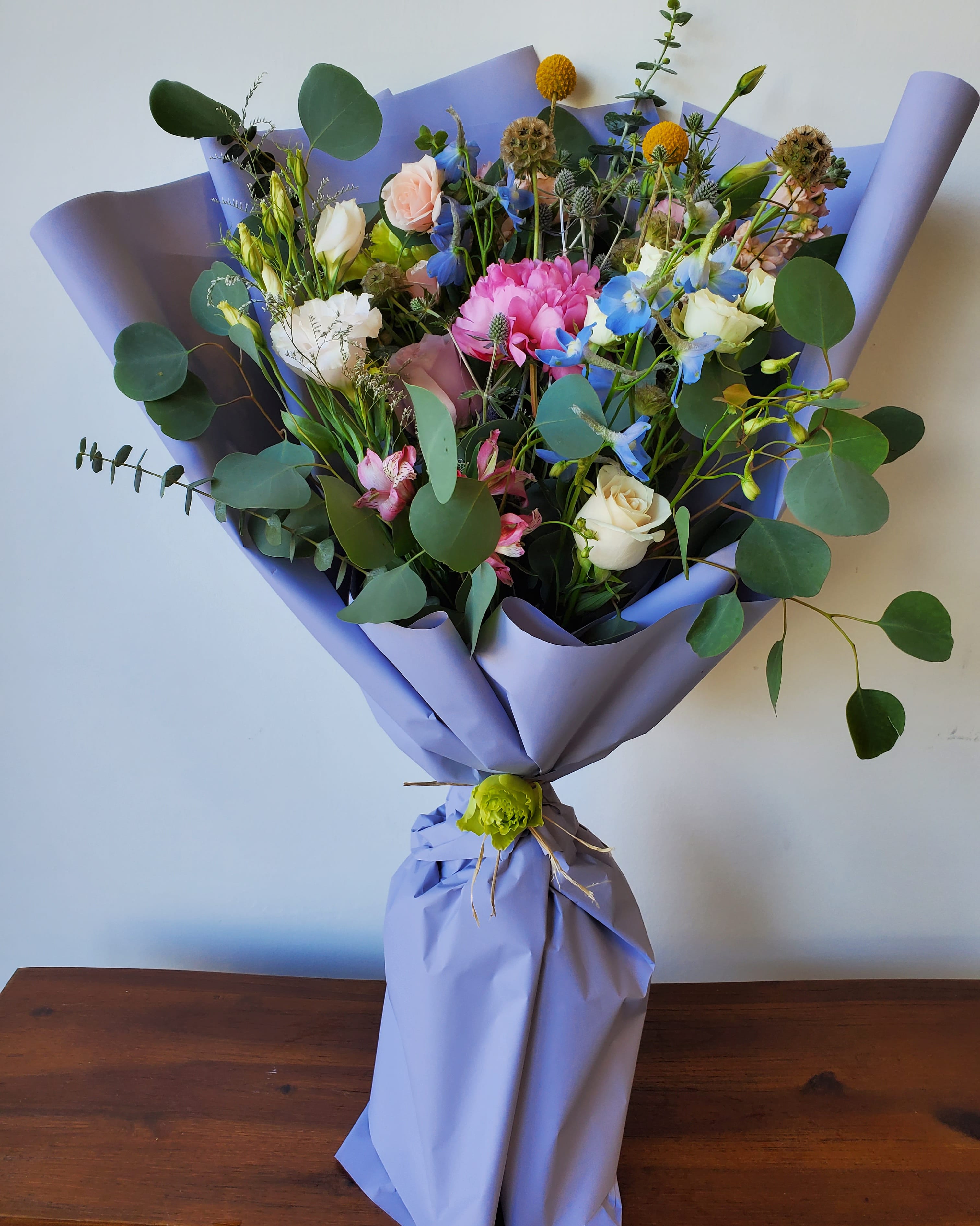 Mixed bouquet of pastel flowers wrapped in lavender paper