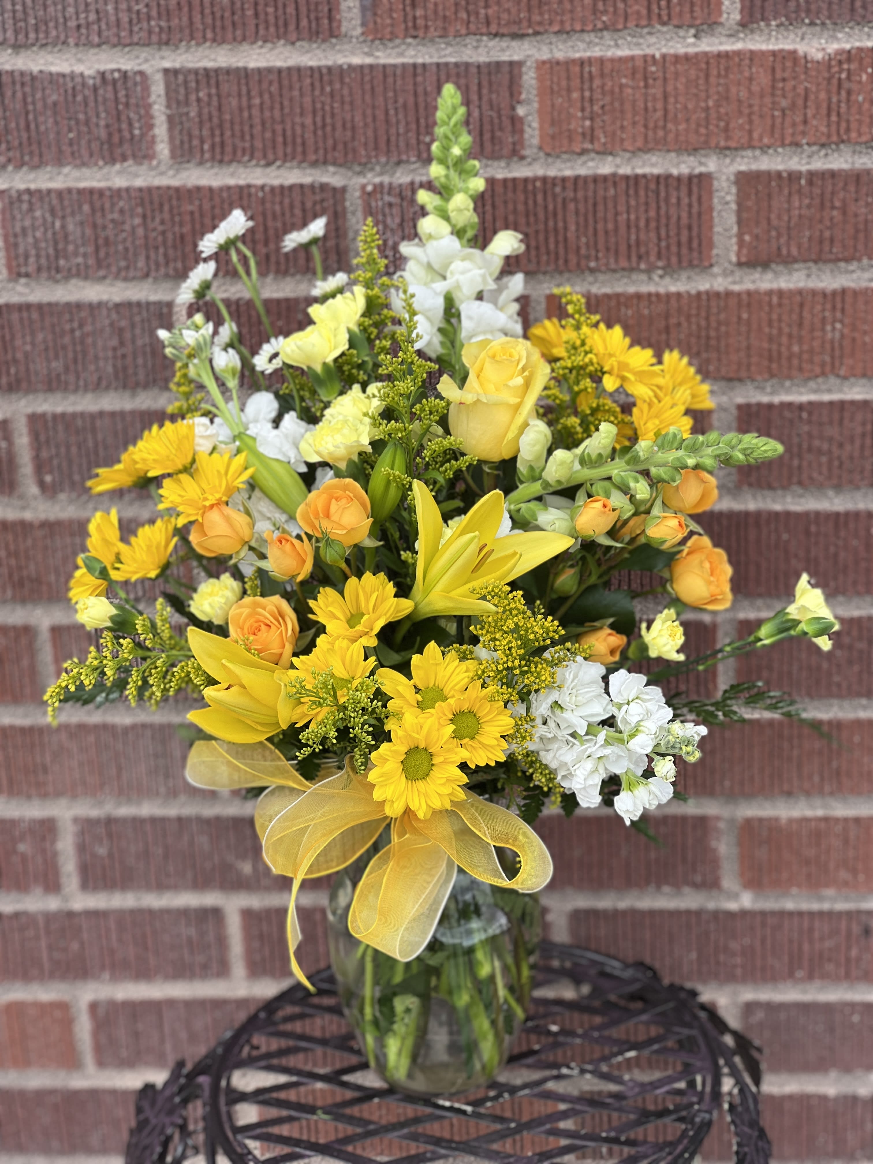 Yellow and white mixed bouquet in a glass vase with a yellow ribbon