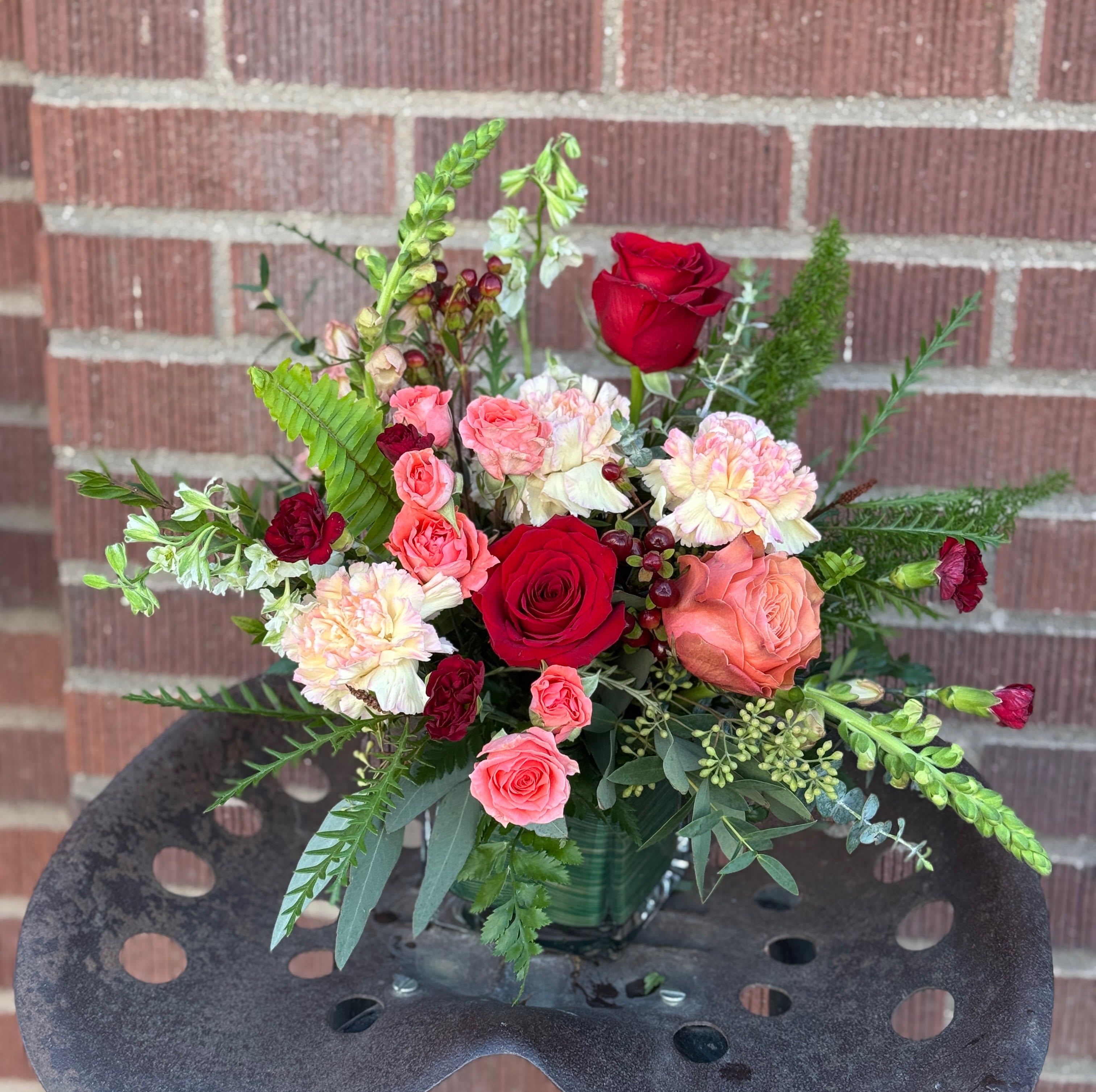 Mixed bouquet of red and pink roses with carnations in a glass vase